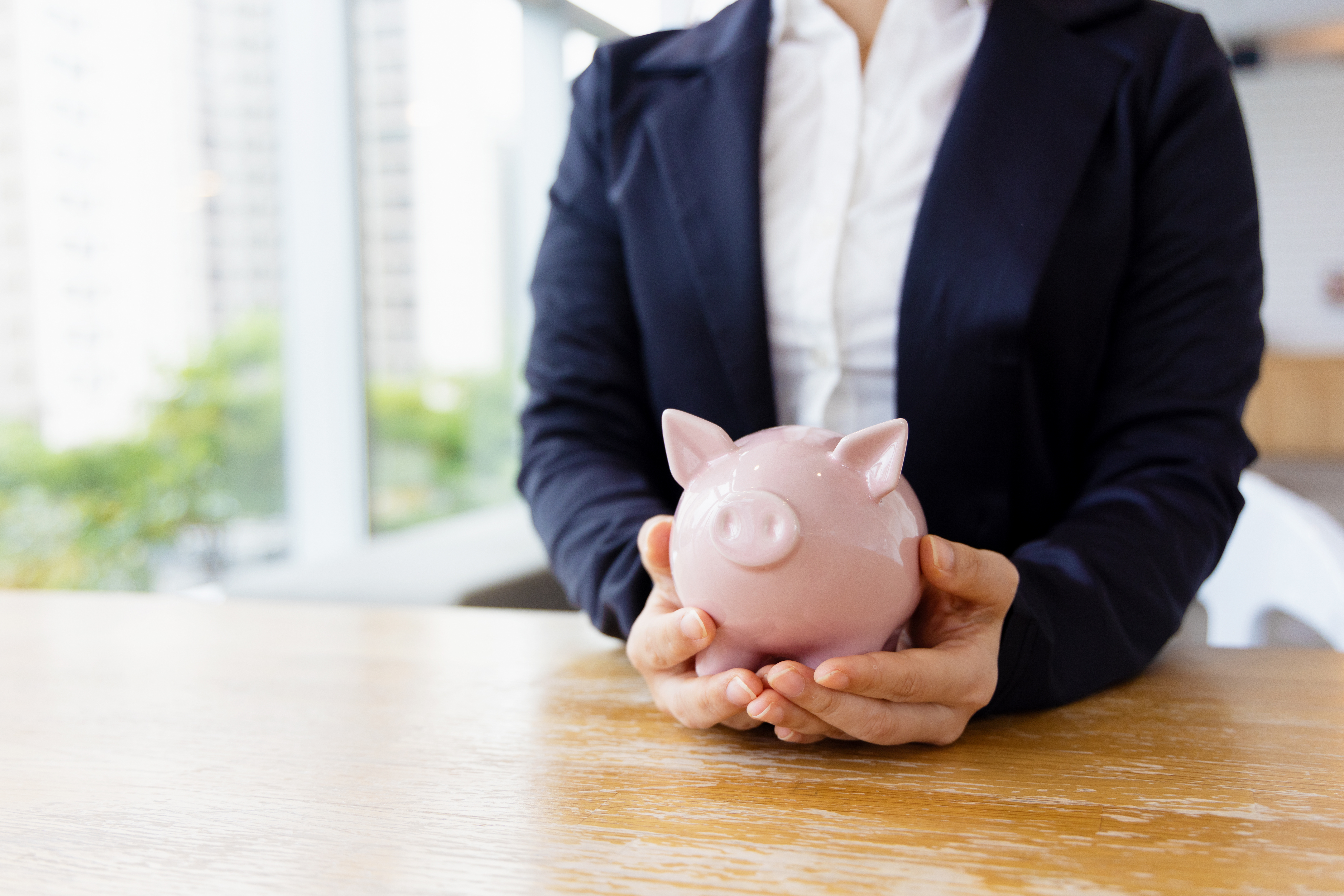 Woman putting coin in piggy bank, saving money